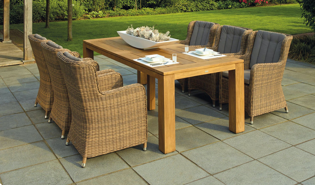 A set of table and chairs on a hardscape patio. A paver patio extends from the house.